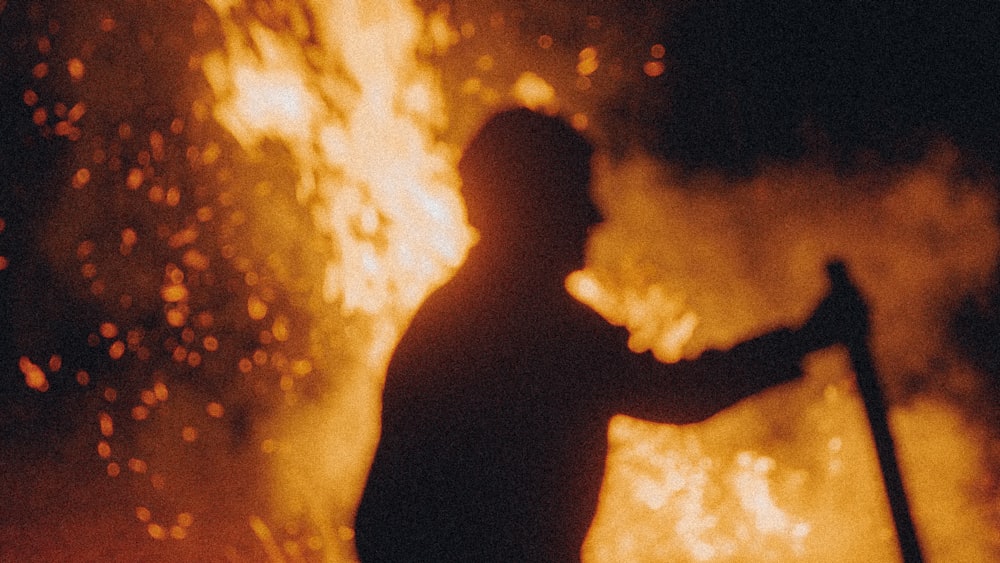 a man holding a stick in front of a fire