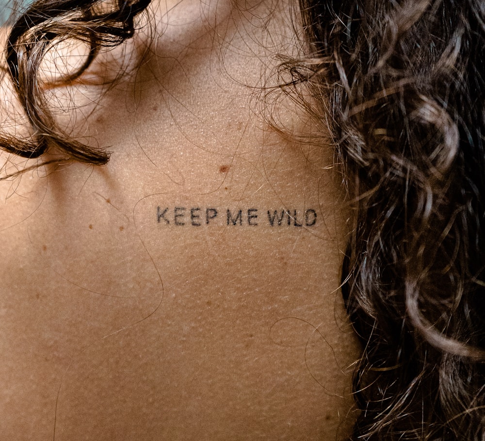 Una mujer con un tatuaje en la espalda diciendo Keep Me Wild