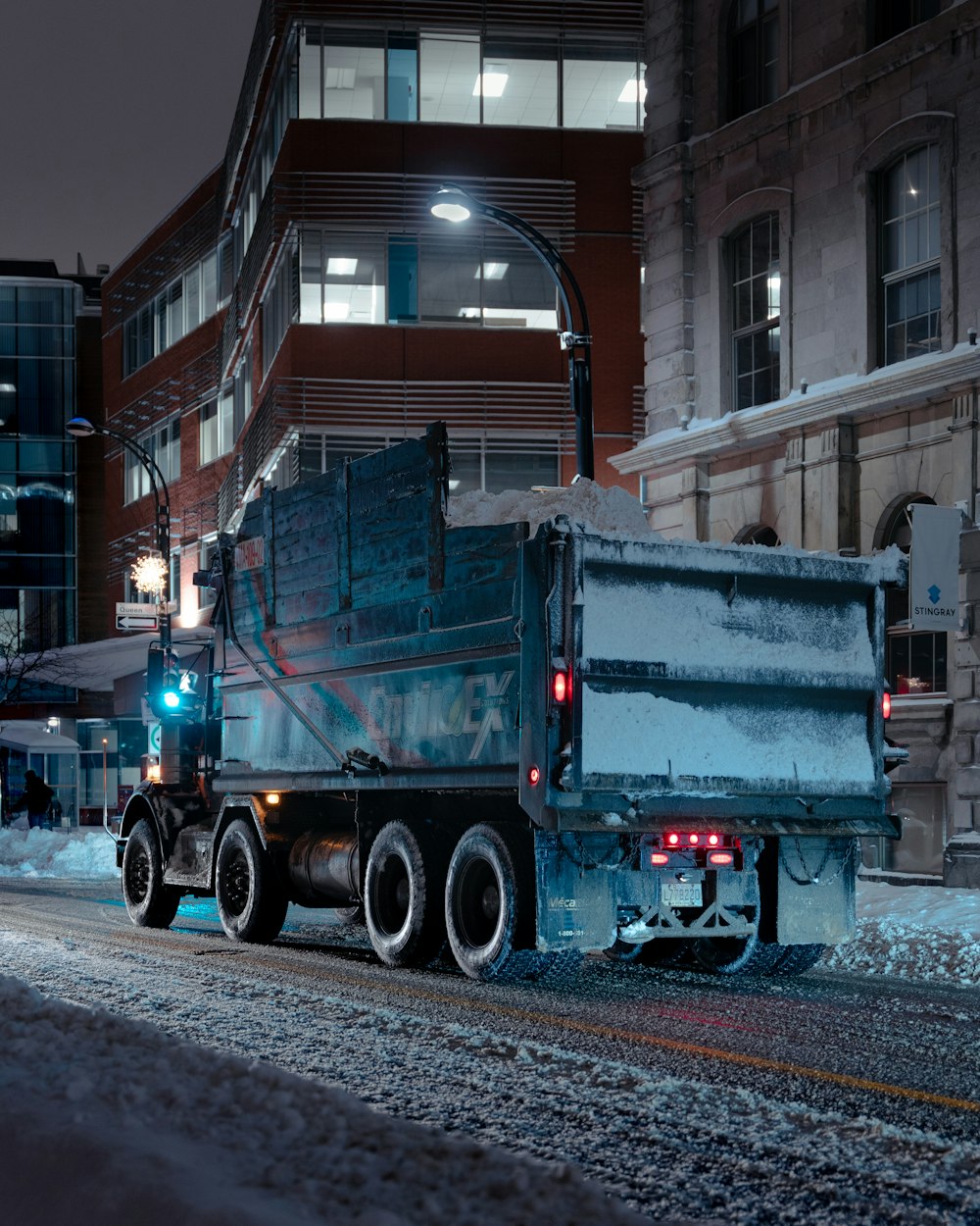 a dump truck driving down a street at night