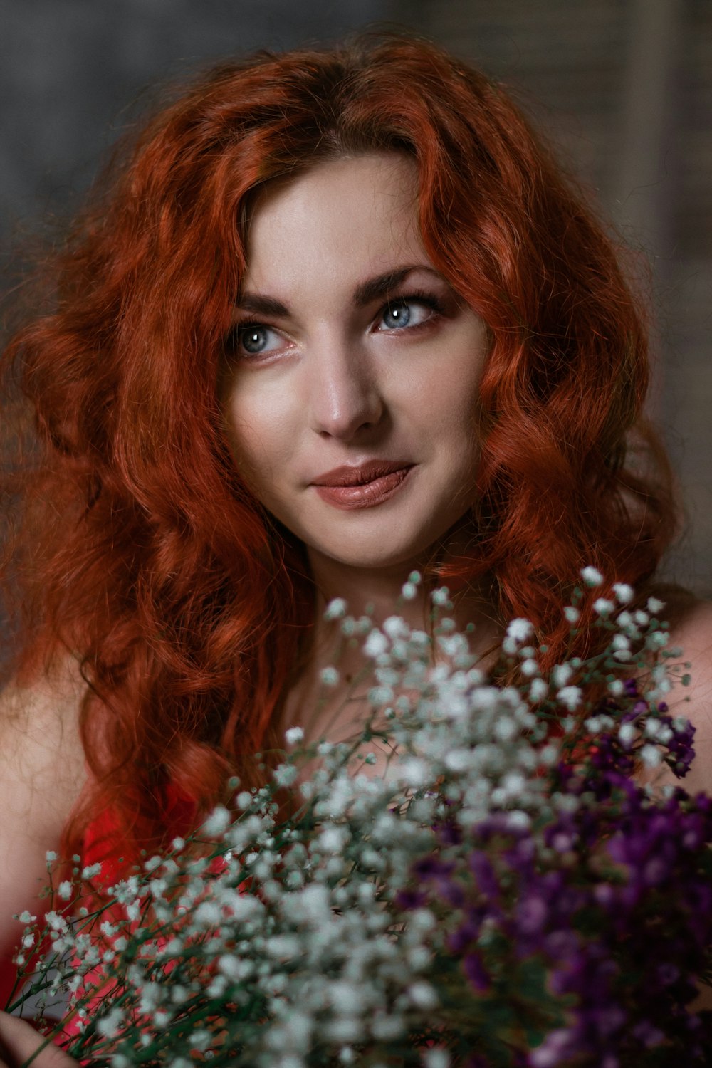 a woman with red hair holding a bouquet of flowers