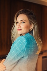 a woman standing in a kitchen wearing a sweater