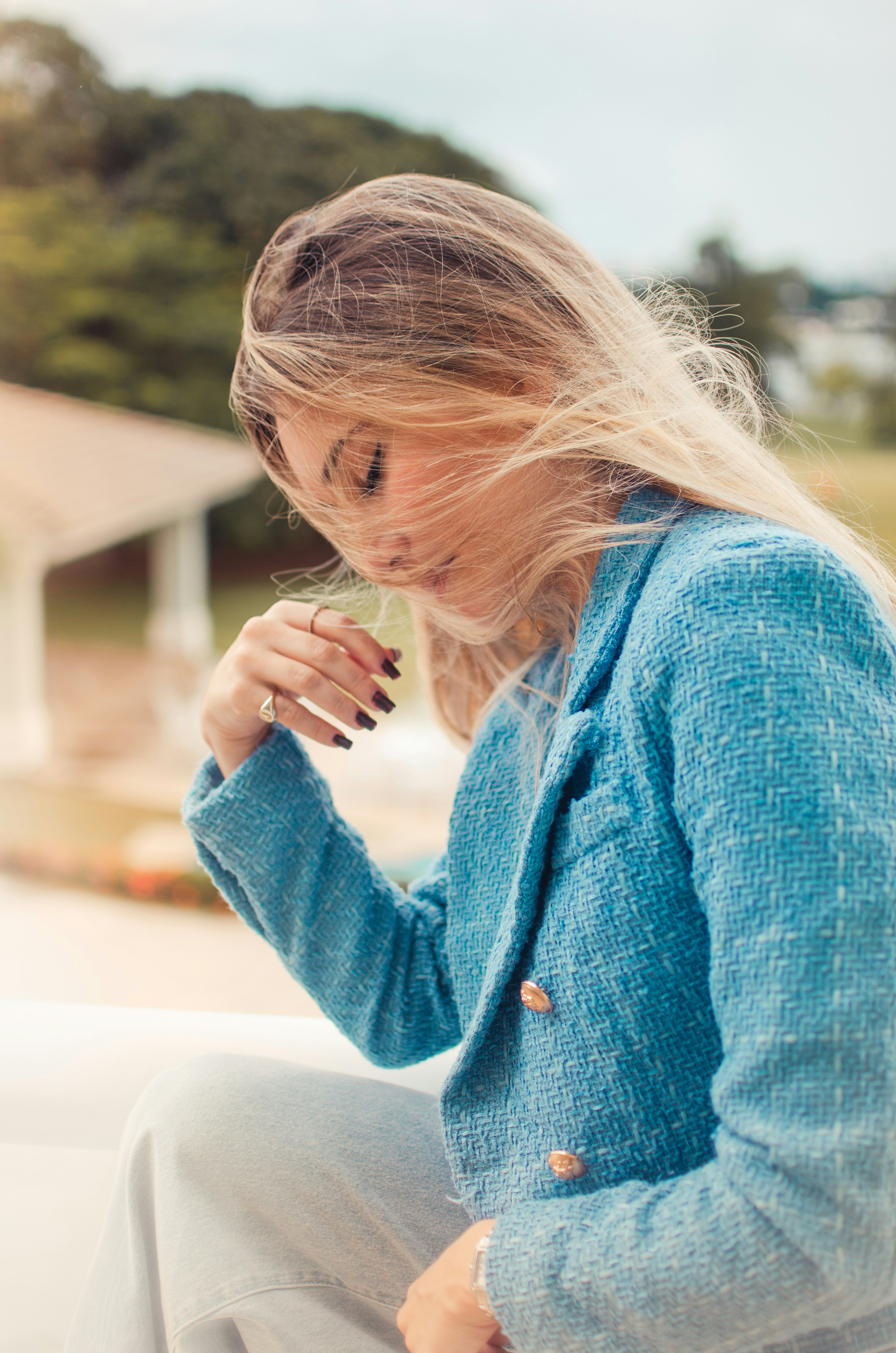 a woman sitting on a ledge with a cigarette in her hand