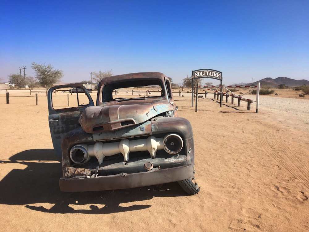 an old truck sitting in the middle of a desert