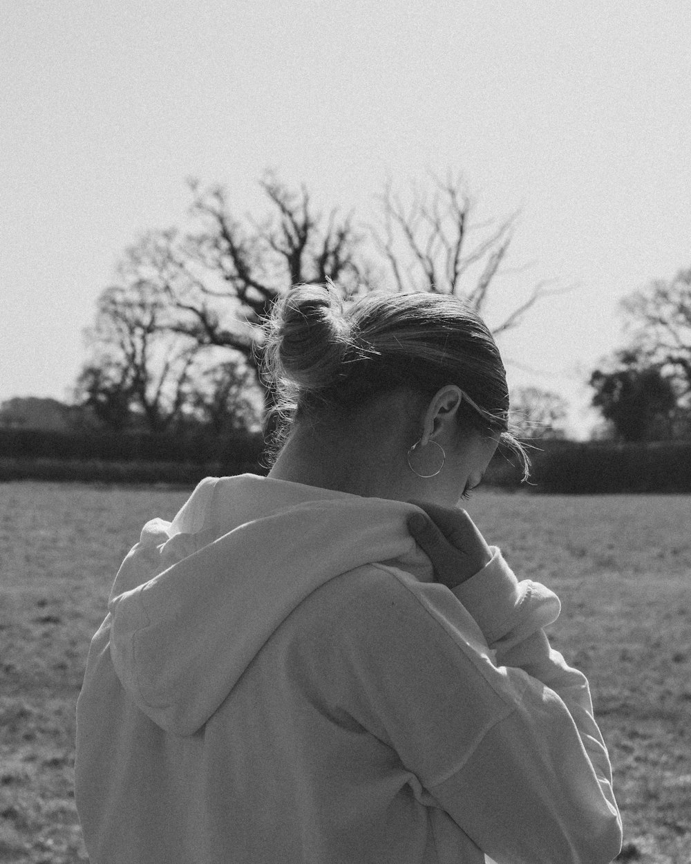 a woman standing in a field wearing a hoodie