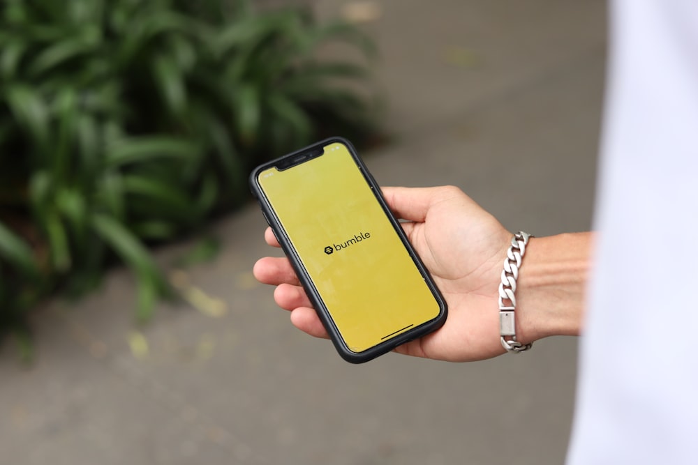 a person holding a yellow cell phone in their hand