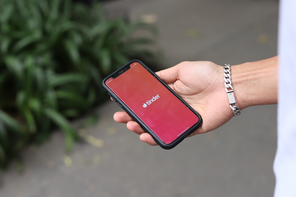 a person holding a red cell phone in their hand