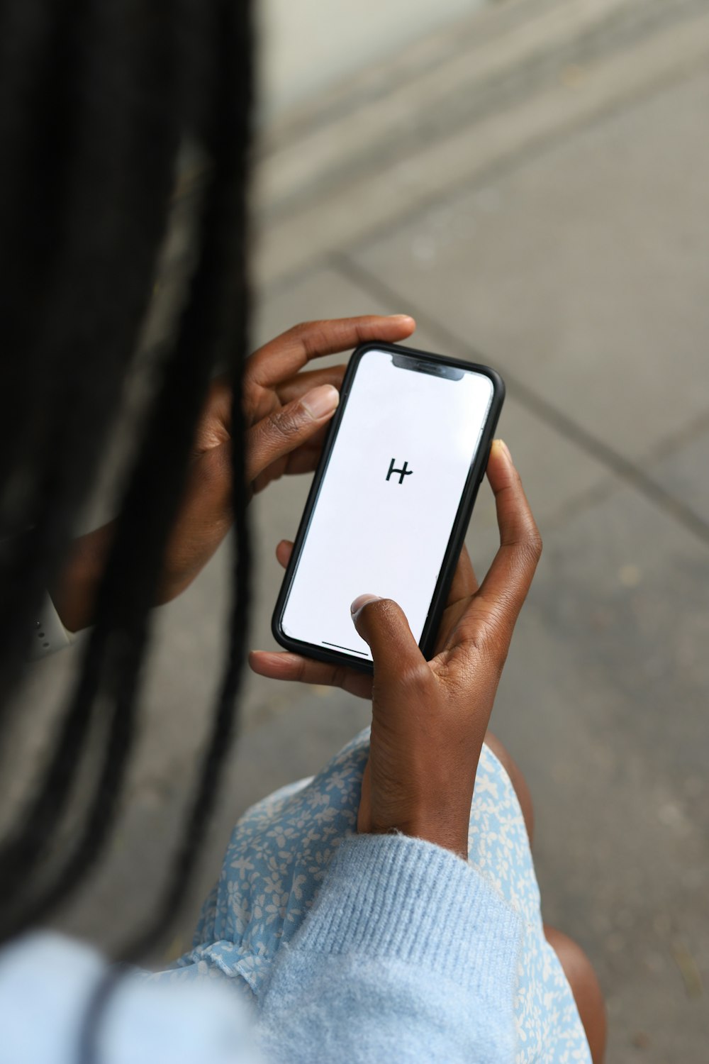 Una mujer sosteniendo un teléfono celular con una h en la pantalla