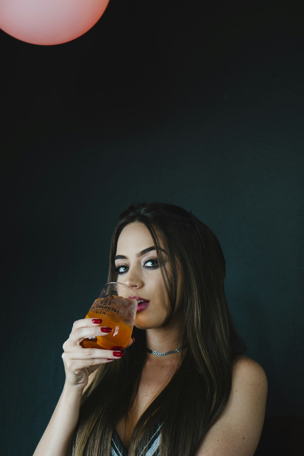a woman holding a drink and looking at the camera