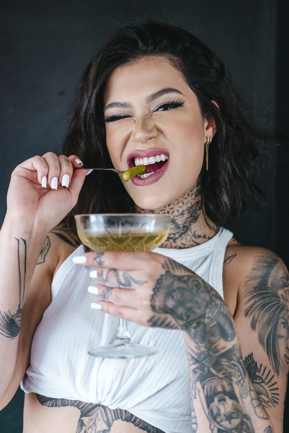 uma mulher com tatuagens segurando um copo de vinho