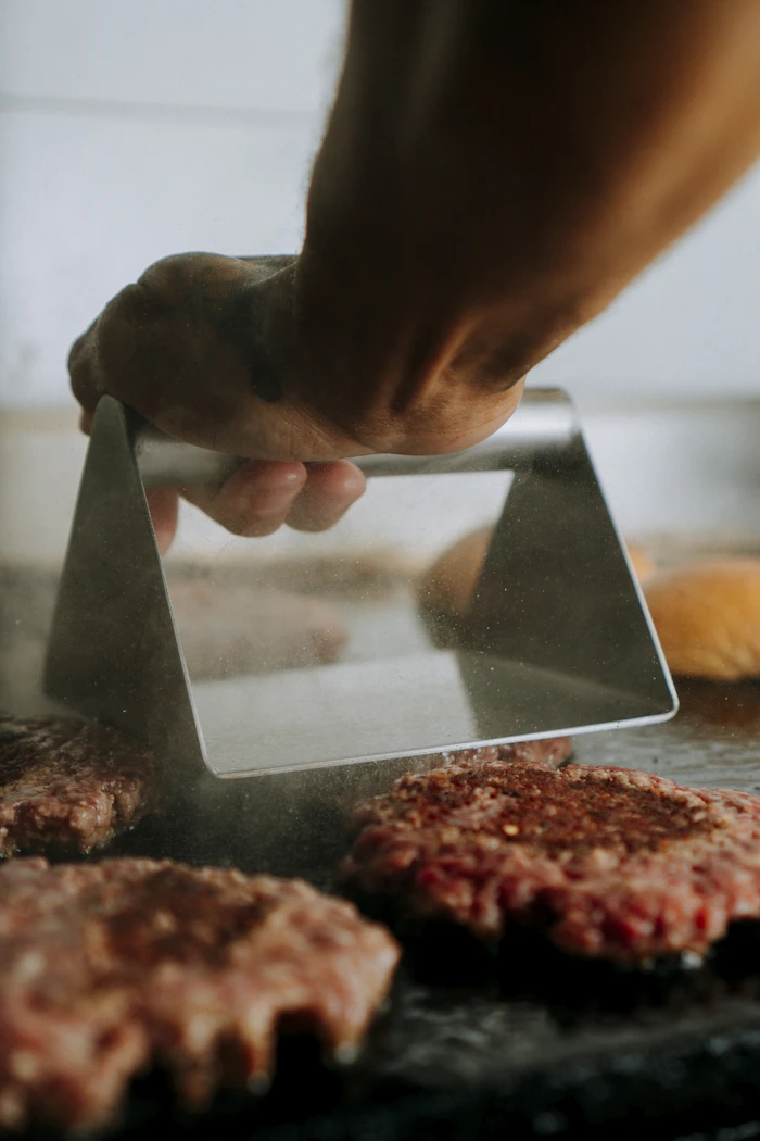 A patty being smashed flat on the griddle