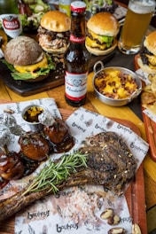 a wooden table topped with lots of food and drinks. beer and bbq