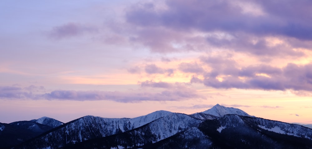 a group of mountains covered in snow under a cloudy sky