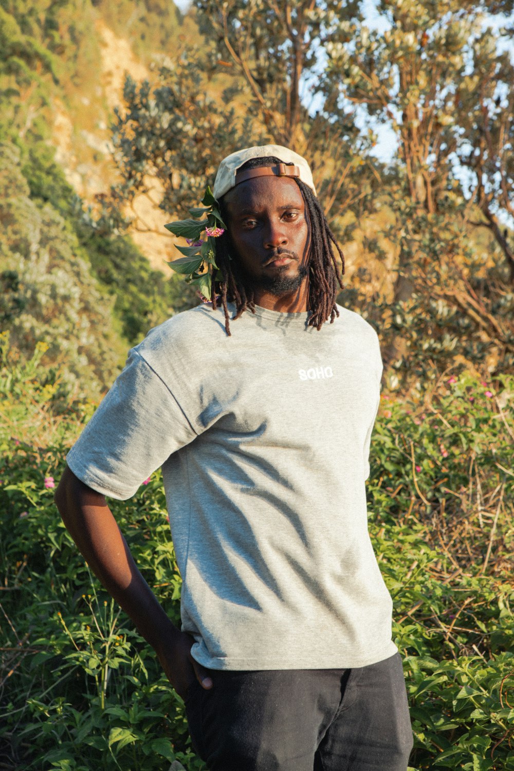 a man with dreadlocks standing in a field