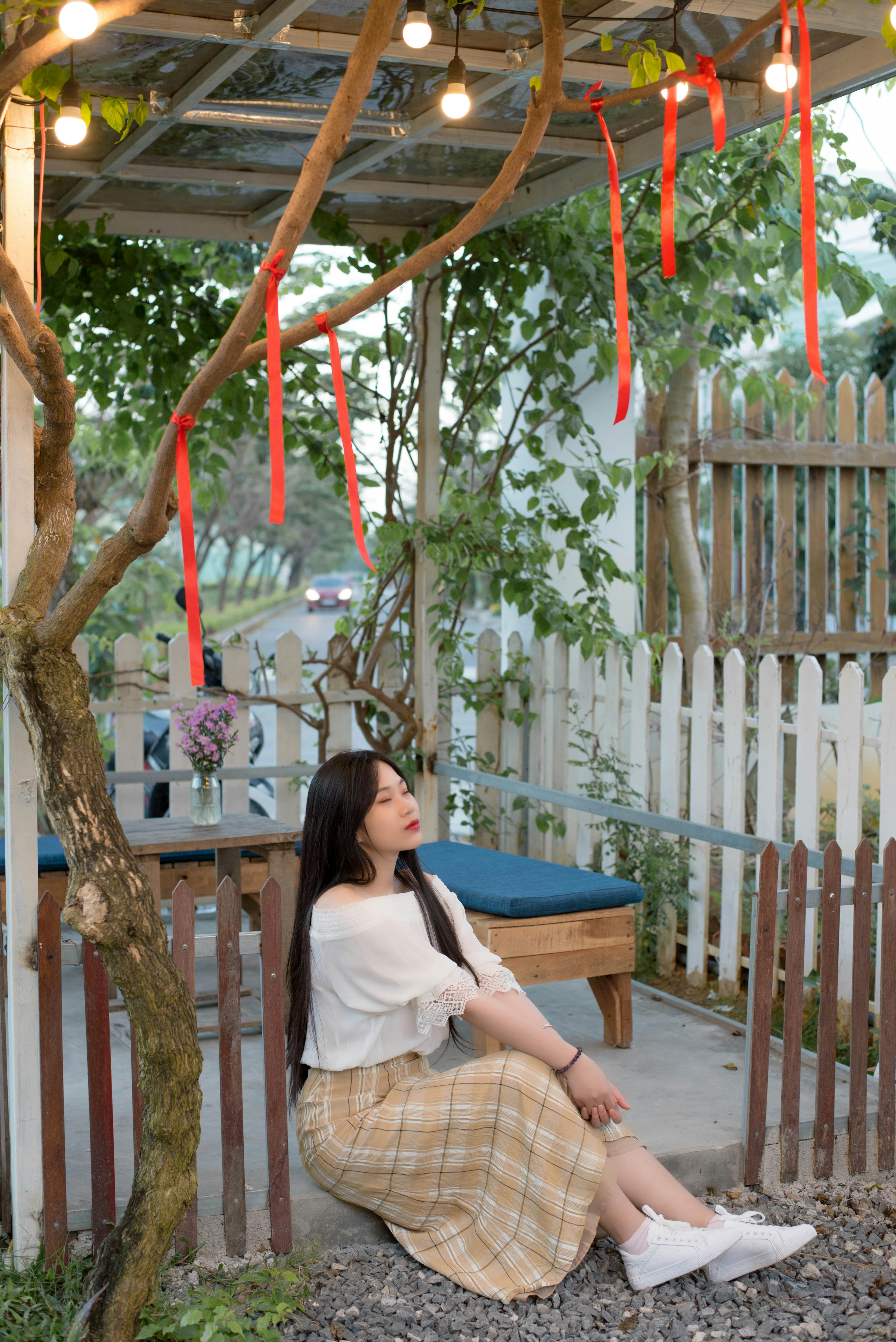 a woman sitting on a bench under a tree
