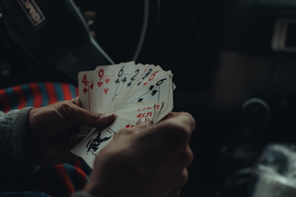 a person holding four playing cards in their hands