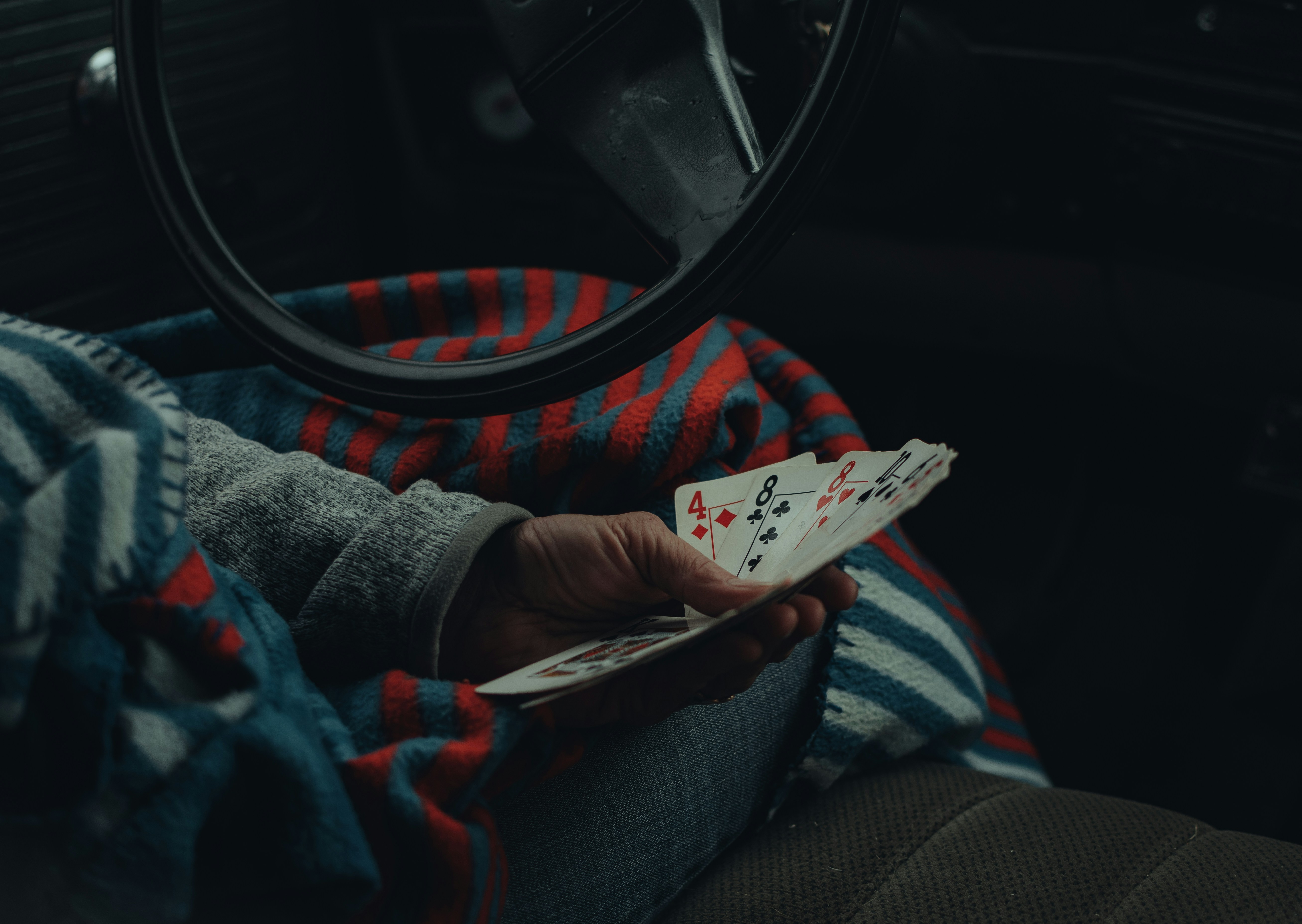 a person sitting in a car holding a deck of cards