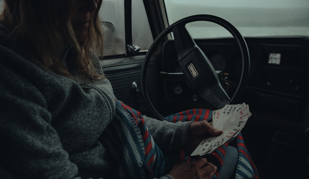 a woman sitting in a car holding a piece of paper