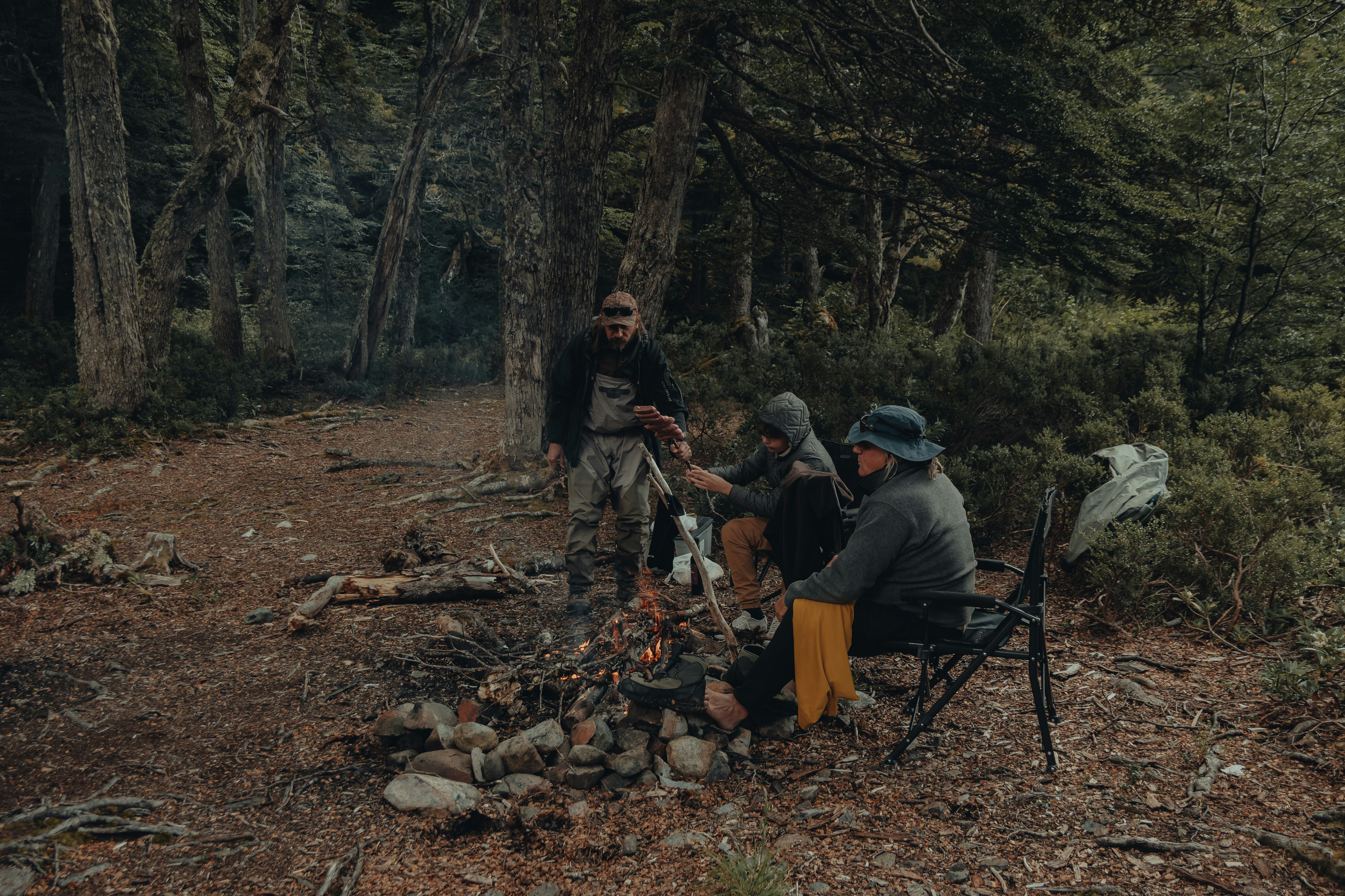 a group of people sitting around a fire in the woods
