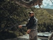 a man standing next to a tree near a body of water