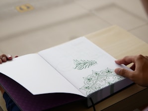 a person is holding a book open on a table