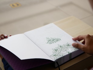 a person is holding a book open on a table