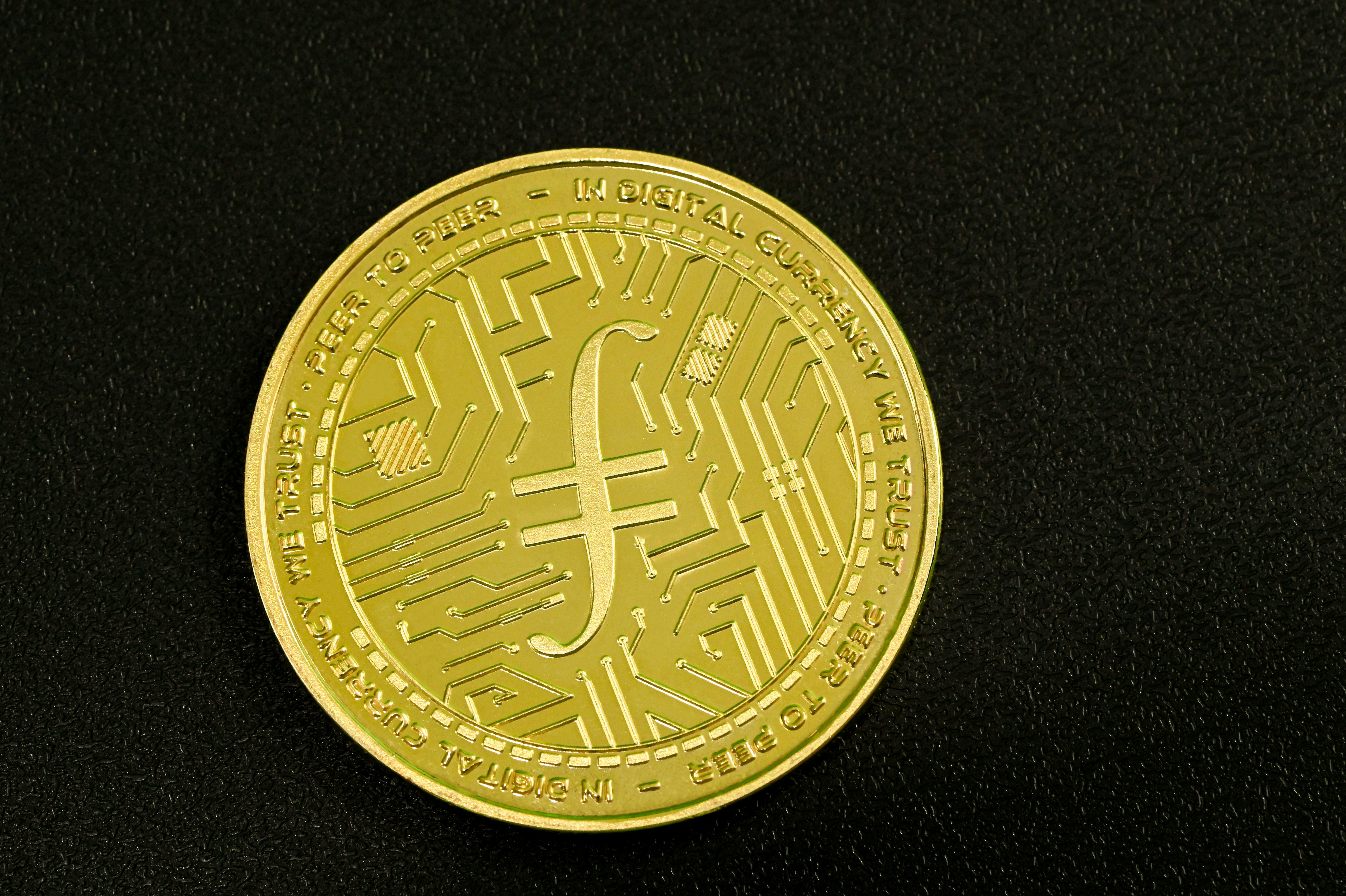 A gold Filecoin placed on a dark surface