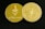 Two gold-colored coins are displayed on a dark surface. One coin features the Ethereum symbol and the word 'ethereum,' while the other has a circuit design and text around the edge.
