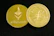 Two gold-colored coins are displayed on a dark surface. One coin features the Ethereum symbol and the word 'ethereum,' while the other has a circuit design and text around the edge.