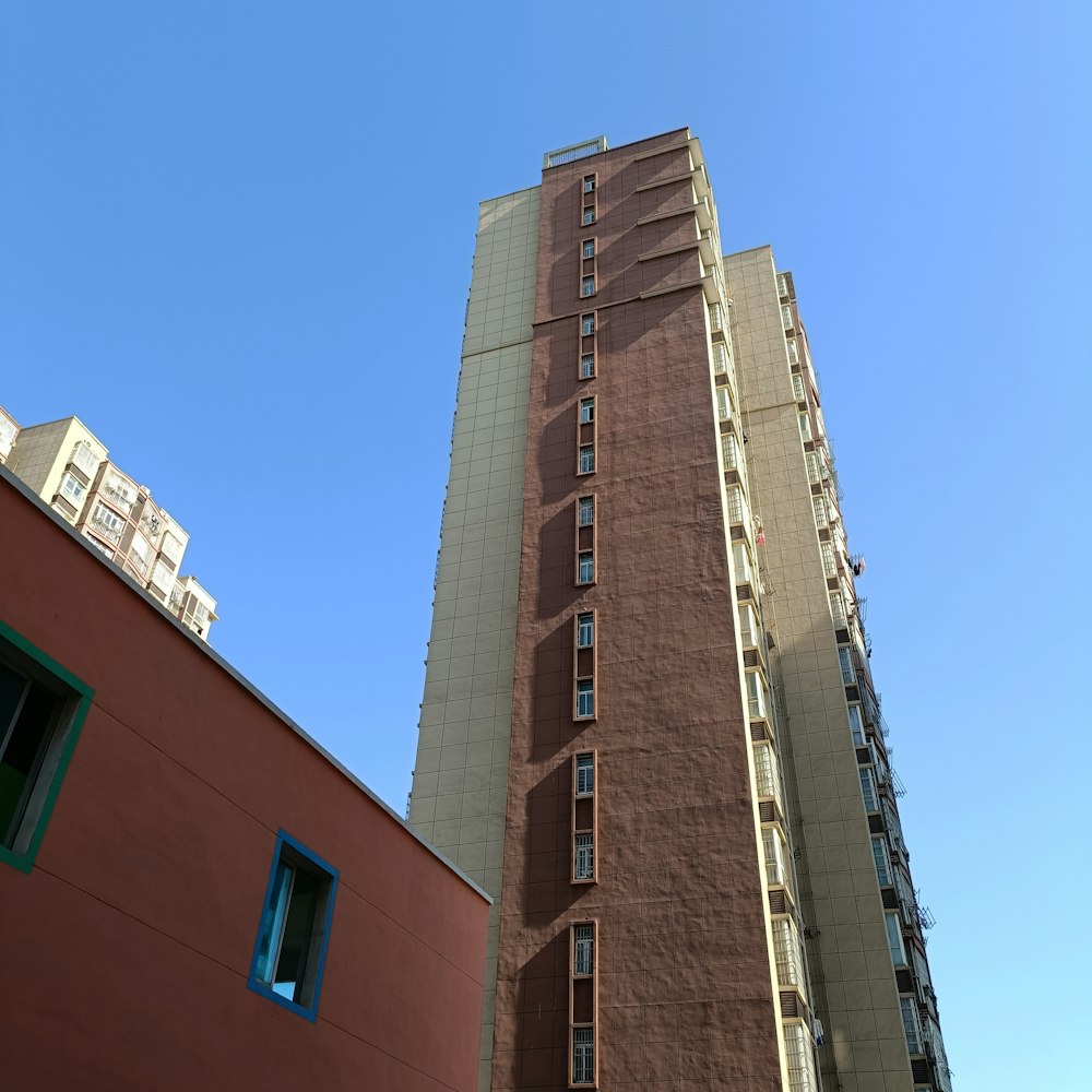 a tall brown building with windows next to a red building