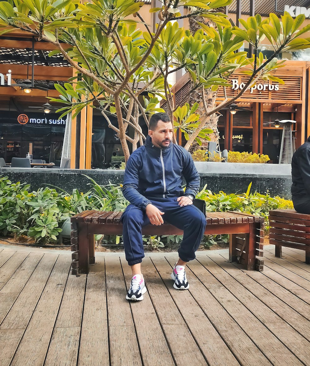 a man sitting on a bench in front of a tree