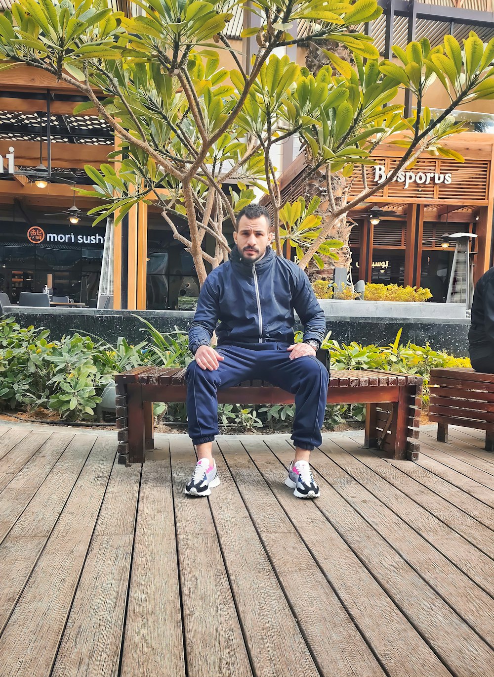 a man sitting on a bench in front of a tree