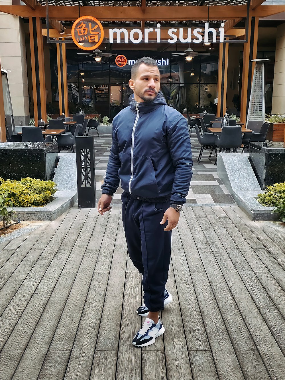 a man standing on a boardwalk in front of a restaurant