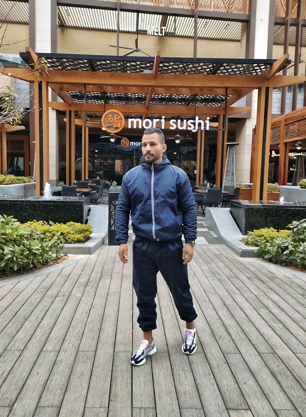 a man standing on a boardwalk in front of a building