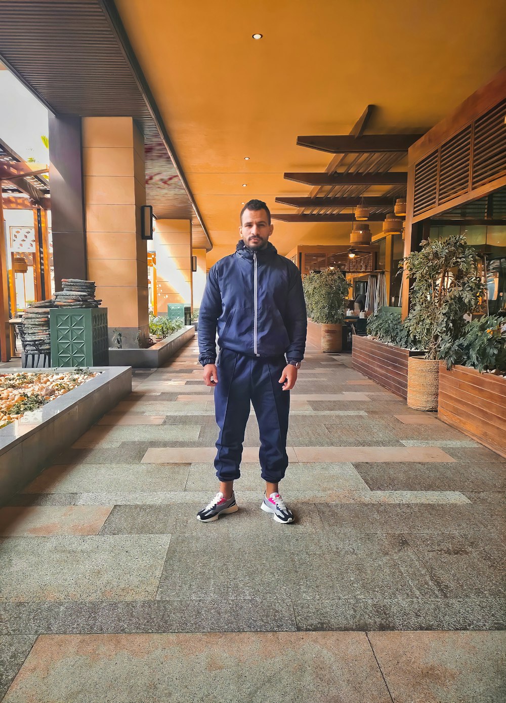 a man standing on a tiled walkway in a building