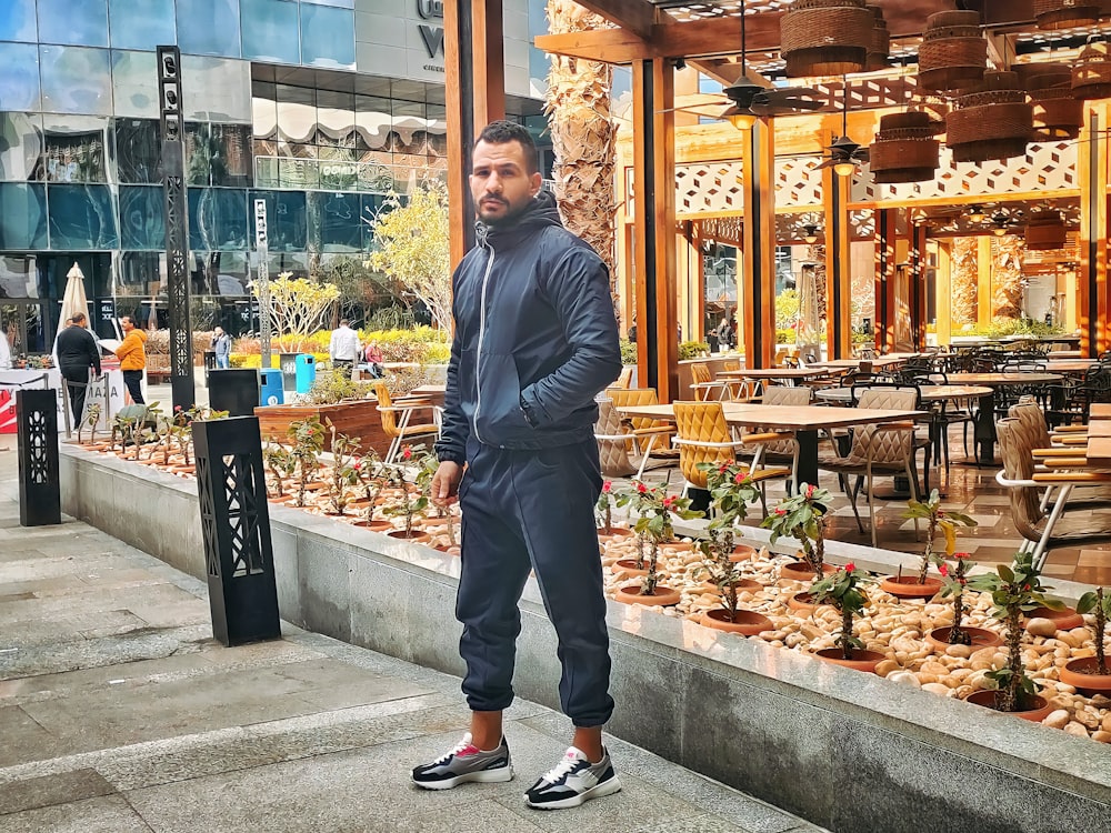 a man standing in front of a store filled with plants