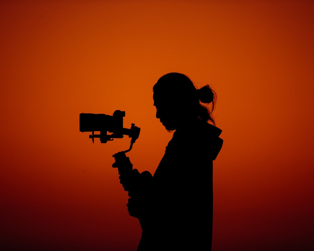 a silhouette of a woman holding a camera