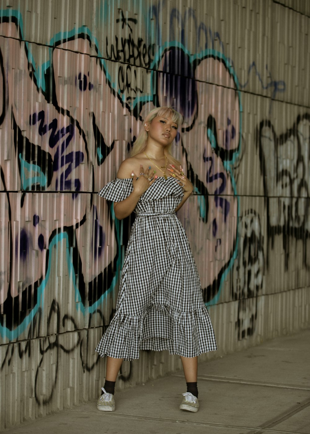 a woman standing in front of a wall covered in graffiti