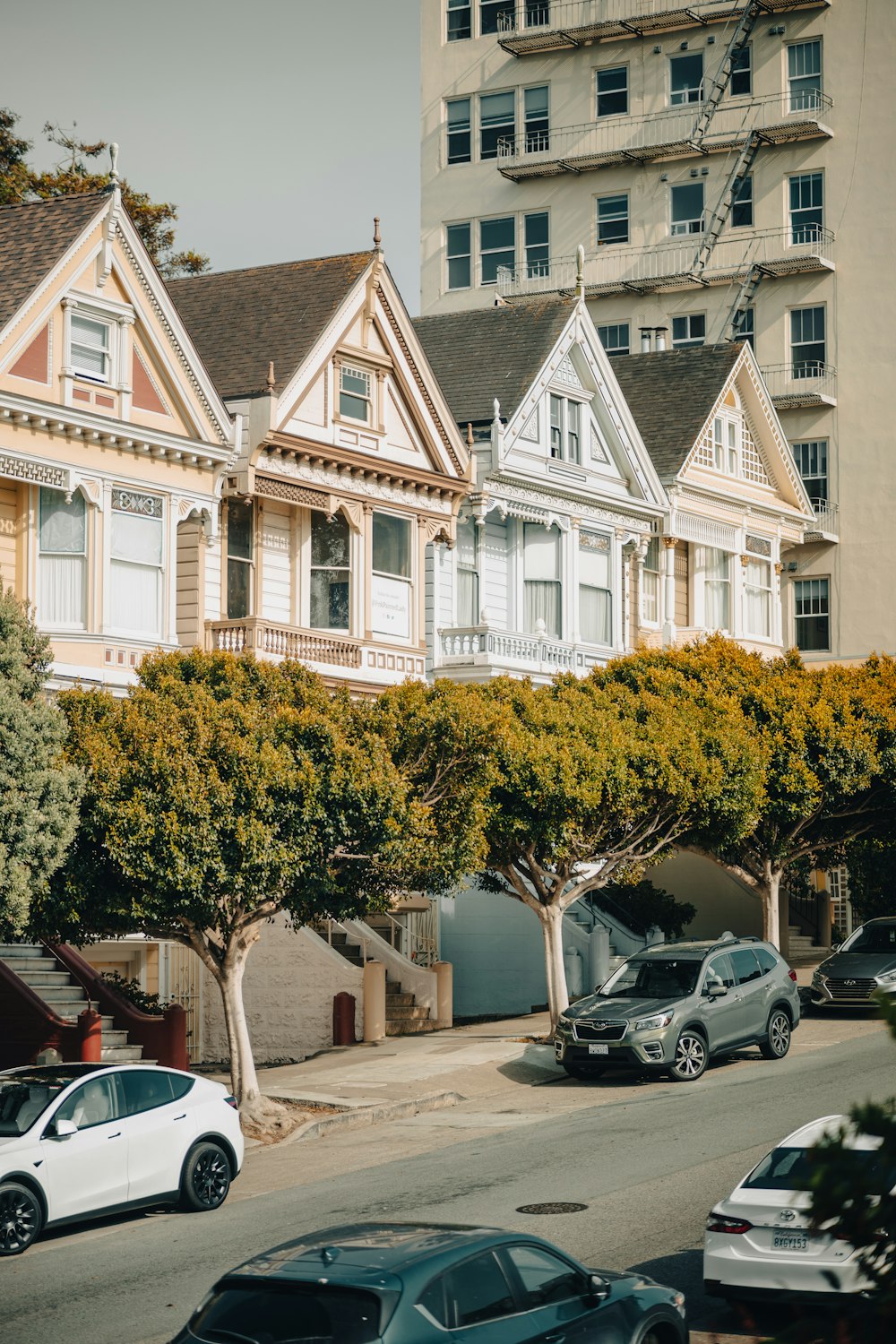 a row of houses with cars parked on the street