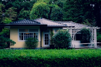 a small yellow house surrounded by trees and bushes