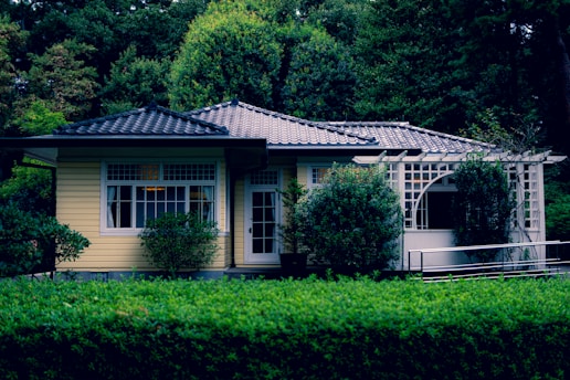 a small yellow house surrounded by trees and bushes