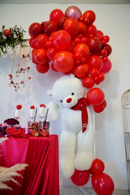 a large white teddy bear with red balloons