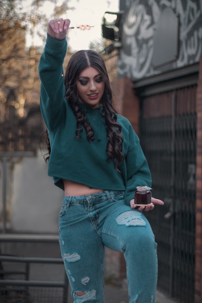 a woman in a green sweatshirt and ripped jeans