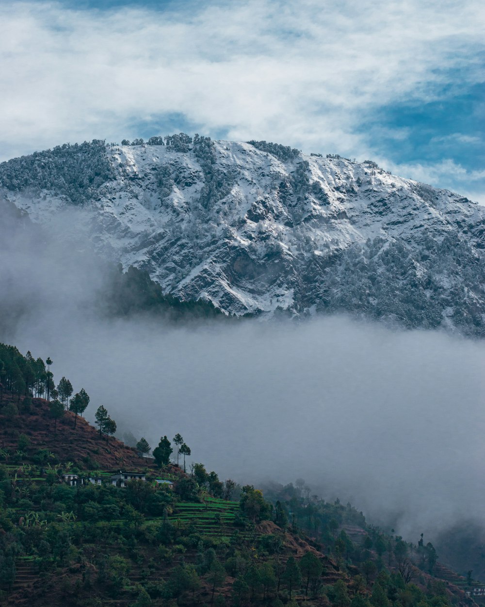 a mountain covered in snow and clouds on a cloudy day