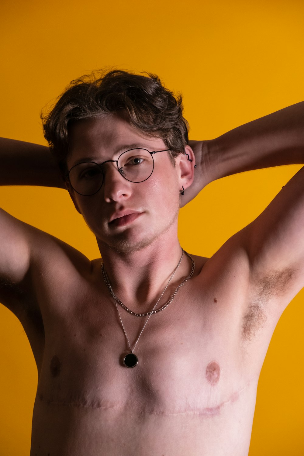 a shirtless man wearing glasses and a necklace