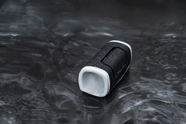 A compact portable speaker with water droplets, hinting at its waterproof feature.
