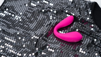 a pink object sitting on top of a black sequin bag