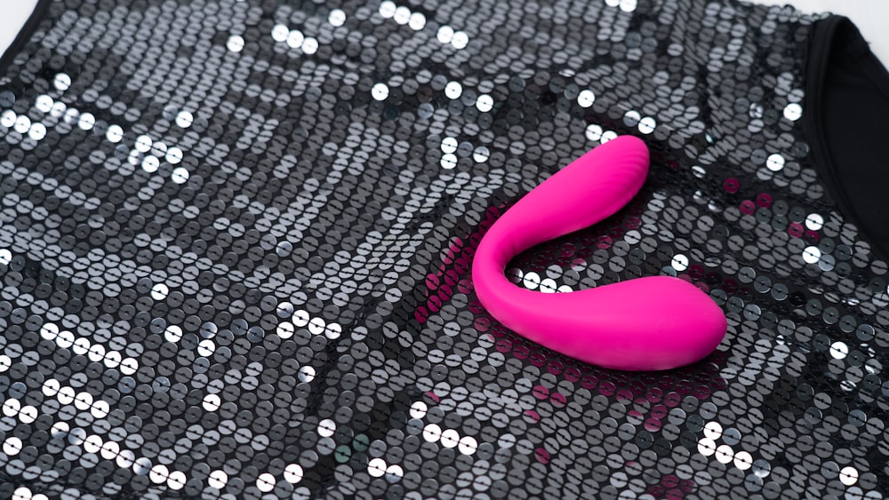 a pink object sitting on top of a black sequin bag