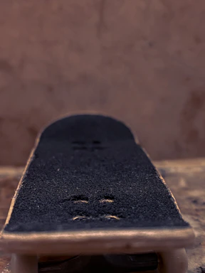 A close-up of a skateboarder’s hand gripping a deck, with vibrant graffiti in the background.