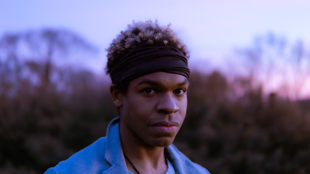 a young man with a headband on standing in a field