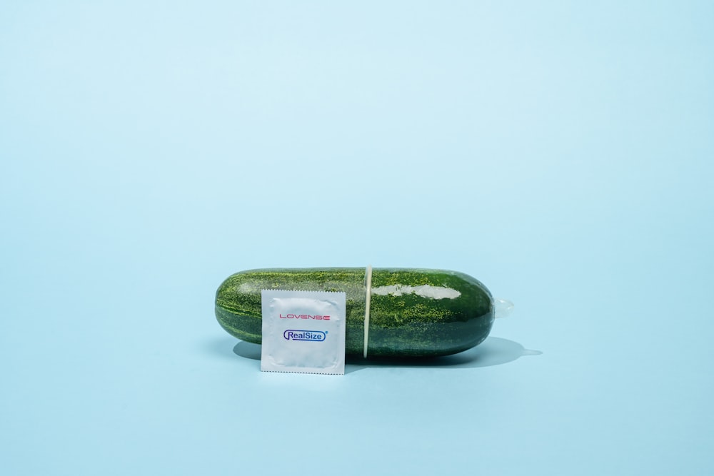 un concombre avec une étiquette dessus assis sur une surface bleue